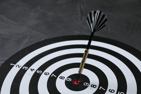 Targeting. Dart board with arrow on gray background, closeup