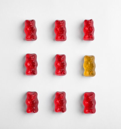 Orange jelly bear among red ones on white background, flat layの写真素材