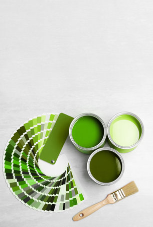 Cans with paint in shades of green, brush and color palette on white background, top view. Space for textの写真素材