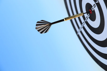 Targeting. Dart board with arrow against blue sky, closeupの写真素材
