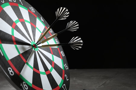 Targeting. Dart board with arrows on dark background, closeup. Space for text