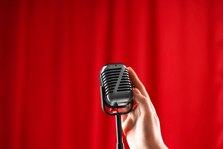 Woman with vintage microphone against red curtain, closeupの写真素材