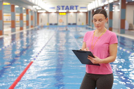 Swimming coach taking notes at indoor pool. Space for textの写真素材