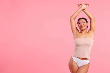 Woman showing hairless armpits after epilation procedure on pink background, space for textの写真素材