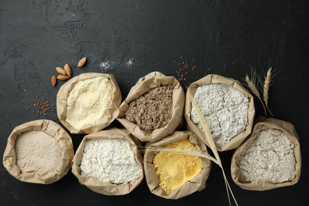 Different types of flour in paper bags on black table, flat layの写真素材