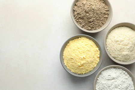 Different types of flour in bowls on light gray table, flat lay. Space for textの写真素材