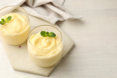 Tasty vanilla pudding with mint on white wooden table. Space for textの写真素材