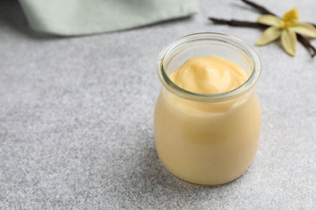 Tasty vanilla pudding, pods and flower on gray table, closeup. Space for textの写真素材