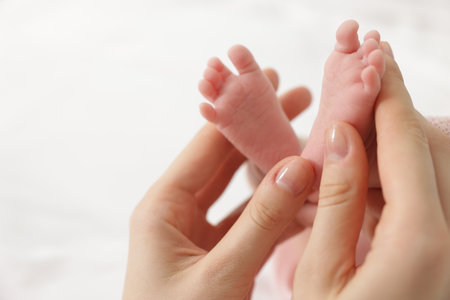 Mother with her little baby on bed indoors, closeup. Space for textの写真素材