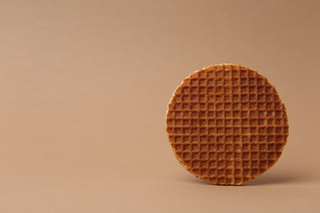 One tasty round waffle on brown background. Space for textの写真素材