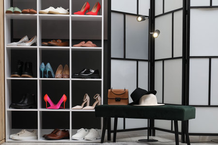 Shoe storage. Shelving unit with different footwear, accessories and ottoman indoorsの写真素材