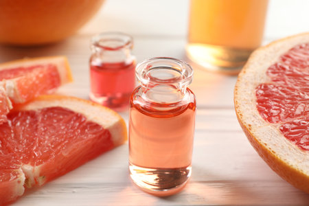 Open perfume bottles with aromatic essential oils and slices of grapefruit on white wooden table, closeupの写真素材