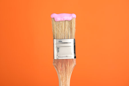 Brush with pink paint on orange background, closeupの写真素材