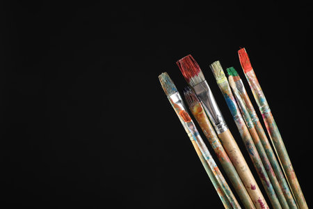 Many dirty paintbrushes on black background, closeup. Space for textの写真素材