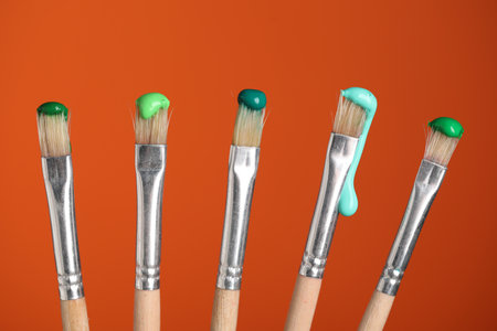 Many brushes with color paints on orange background, closeupの写真素材