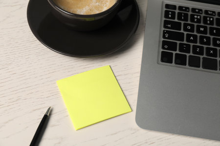 Sticky note, pen, coffee and laptop on white wooden table, above viewの写真素材