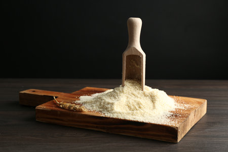 Pile of flour and scoop on dark wooden table against black background, closeupの写真素材