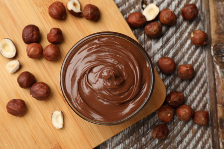 Chocolate hazelnut spread in bowl and nuts on wooden table, flat layの写真素材