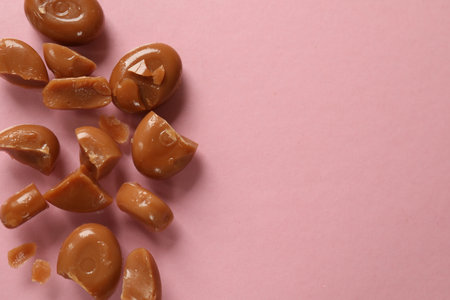Many tasty caramel candies on light pink background, flat lay. Space for textの写真素材
