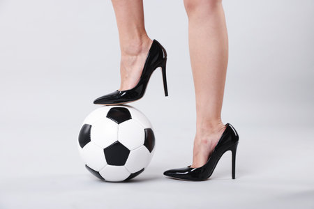 Woman in high heeled shoes with soccer ball on light background, closeupの写真素材