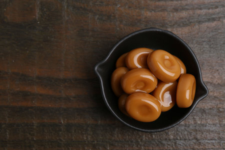 Tasty sweet caramel candies on wooden table, top view. Space for textの写真素材