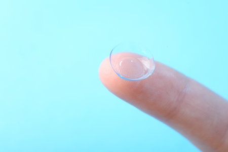 Woman with contact lens on light blue background, closeup.の写真素材