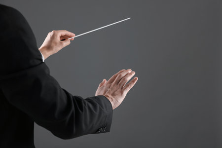Professional conductor with baton on gray background, closeup. Space for textの写真素材