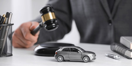 Closeup of judging striking gavel at table, focus on toy car. Banner designの写真素材