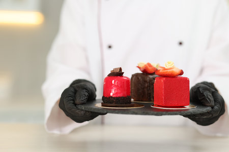 Confectioner with tasty desserts at white table in kitchen, closeupの写真素材