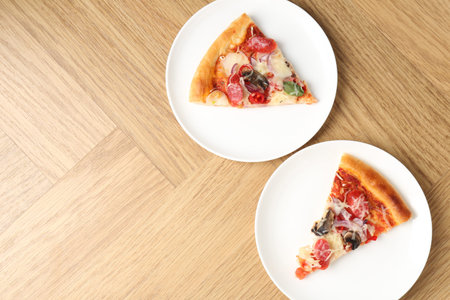 Slices of pizza with thin smoked sausages served on wooden table, flat lay. Space for text