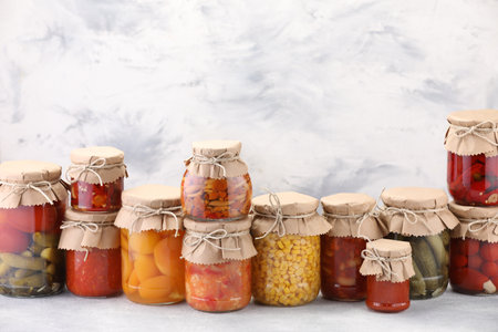 Many jars with different pickled products on light table. Space for textの写真素材