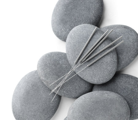 Acupuncture needles and spa stones on white background, flat layの写真素材