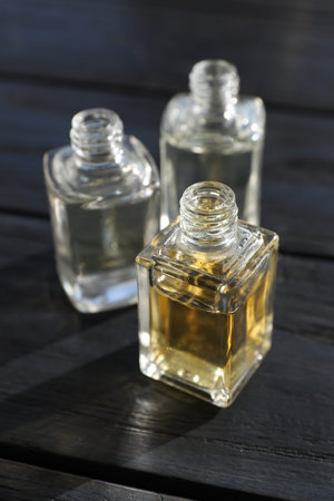 Perfume bottles with aromatic oils on black wooden background, closeup