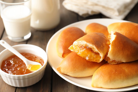 Tasty baked patties with orange jam on wooden table, closeupの写真素材