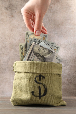 Woman taking dollar banknote from bag at wooden table, closeupの写真素材