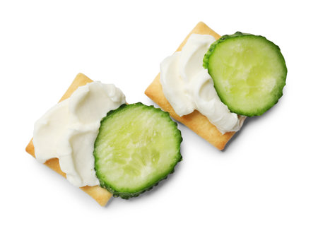 Tasty crackers with cream cheese and cucumber isolated on white, top viewの写真素材