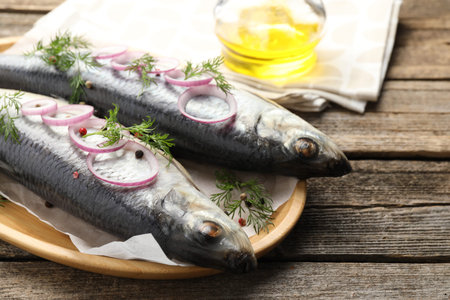 Tasty herrings with spices on wooden table, closeup