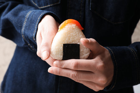 Woman with tasty onigiri (Japanese rice ball) indoors, closeupの写真素材