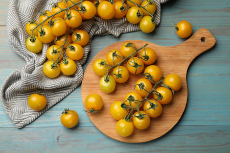 Ripe yellow cherry tomatoes on light blue wooden table, flat layの写真素材