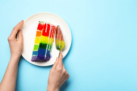 Person with piece of delicious rainbow cake and spatula at light blue table, top view. Space for...