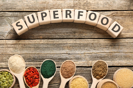 Different superfood powders and word made of cubes on wooden table, flat layの写真素材