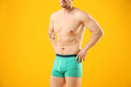Young man in stylish turquoise underwear on orange background, closeupの写真素材