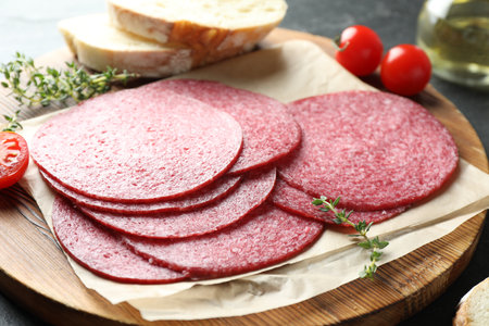 Slices of tasty smoked sausage, bread, tomatoes and thyme on table, closeupの写真素材