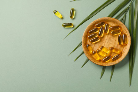 Collagen capsules and leaves on light green background, flat lay. Space for textの写真素材
