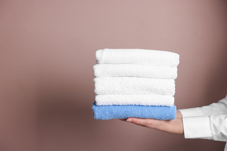 Woman with clean towels on beige background, closeup. Space for textの写真素材