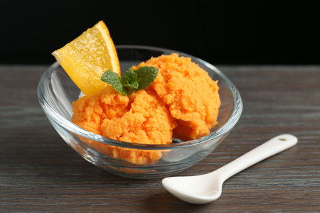 Balls of tasty orange sorbet, fresh fruit, mint and spoon on wooden table, closeupの写真素材