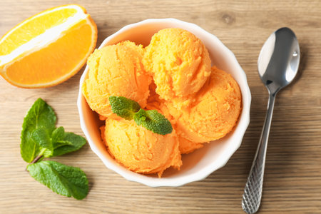 Tasty orange sorbet, fresh fruit slice and mint on wooden table, flat layの写真素材