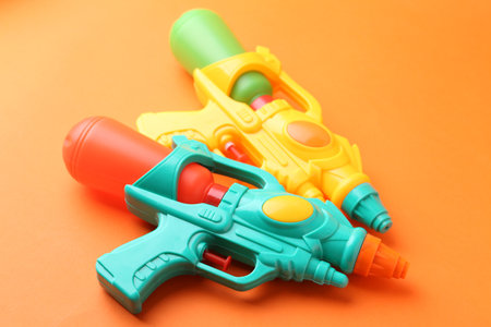 Bright plastic water guns on orange background, closeupの写真素材