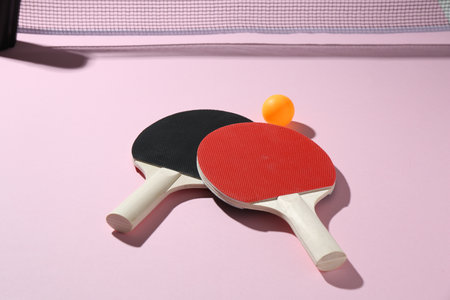 Ping pong rackets, ball and net on pink background, closeupの写真素材