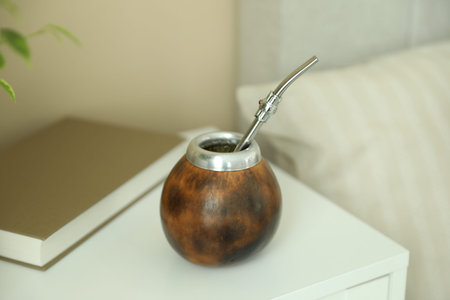 Traditional yerba mate tea and book on bedside table indoors